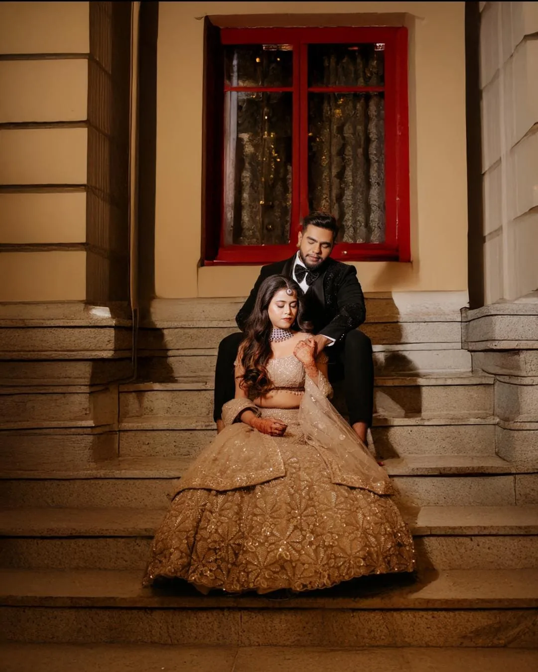 Couple seated on stone steps in wedding attire
